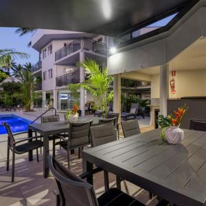 un patio con tavoli, sedie e piscina di UNIT 9 AT MARINA TERRACES a Port Douglas