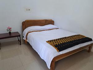 a bed with a wooden headboard and a table at Riung Tiga Empat Tujuh Guesthouse in Riung