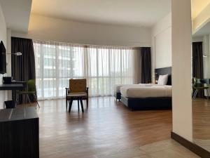 a large hotel room with a bed and a chair at Win Hotel in Sibu