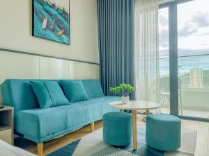 a living room with a blue couch and a table at Grand Hyams Hotel - TMS Tầng 21 View Biển Quy Nhơn - 2PN in Quy Nhon