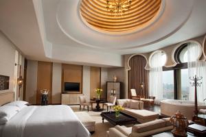 Sheraton Qingyuan Lion Lake Resort في تشينغيوان: غرفة نوم بسرير كبير وغرفة معيشة