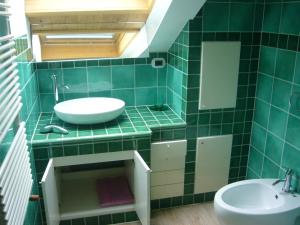 a green tiled bathroom with a sink and a toilet at Case Pizzocco 3 a Santa Giustina in Meano