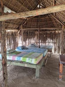 Zimmer mit 2 Betten in einer Strohhütte in der Unterkunft Cabañas tradicionales en isla Aroma in Warsobtugua