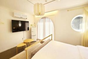 a bedroom with a bed and a desk and a tv at STAY AROUND in Jeju