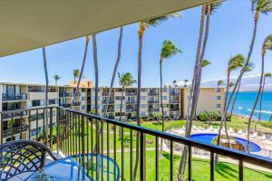 a balcony with palm trees and a view of the ocean at Condos in Kana'i A Nalu in Wailuku