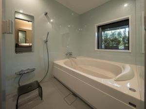 a white bathroom with a tub and a window at LONGINGHOUSE Kyukaruizawa Suwanomori in Karuizawa