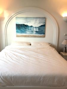 考濤海灘的住宿－Chelona Hua Hin，卧室配有一张白色床,墙上挂有绘画作品
