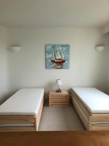 two beds in a room with a painting of a sailboat at Chelona Hua Hin in Khao Tao