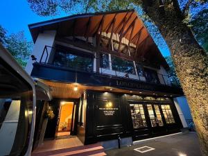 a house with a balcony and a tree at LONGINGHOUSE Kyukaruizawa Suwanomori in Karuizawa