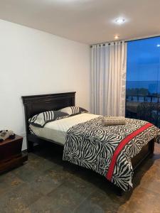 a bedroom with a bed with a zebra blanket and a window at Punta Centinela Apartment in Punta Blanca