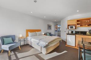 a bedroom with a large bed and a kitchen at Lorenzo Motor Lodge in Christchurch