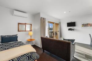 um quarto com uma cama, um sofá e uma televisão em Lorenzo Motor Lodge em Christchurch