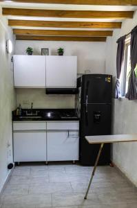 a kitchen with a black refrigerator and white cabinets at Hermosa Cabaña en Isla Tierra Bomba. in Tierra Bomba