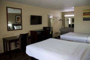 a hotel room with two beds and a desk and a mirror at Legacy Inn - Cookeville in Cookeville