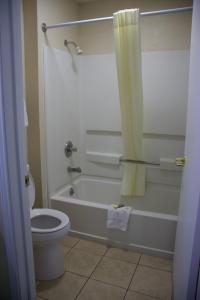 uma casa de banho com uma banheira, um WC e uma cortina de chuveiro. em Legacy Inn - Cookeville em Cookeville