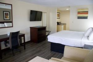 Habitación de hotel con cama, escritorio y TV. en Legacy Inn - Cookeville, en Cookeville