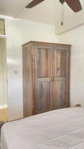 1 dormitorio con 1 cama y armario de madera en Travellers Villa en Roseau