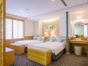 高松市にあるリーガホテルゼスト高松のベッド2台と鏡が備わるホテルルームです。