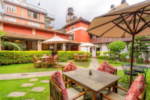a patio with tables and chairs and an umbrella at Hukum Darbar Restaurant & Hotel in Kathmandu