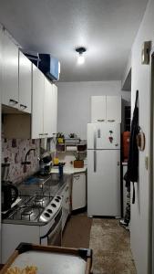 La cuisine est équipée de placards blancs et d'un réfrigérateur blanc. dans l'établissement A Felicidade Mora Aqui!!!!, à Novo Hamburgo