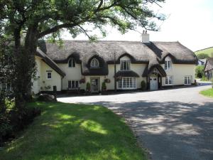 a large white house with a thatched roof at The Royal Oak Exmoor in Winsford