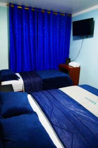 Hostal Valle Andino في El Tambo: غرفة نوم بسريرين وستارة زرقاء