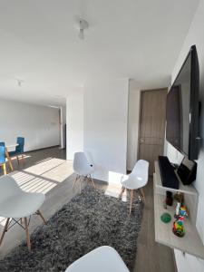 uma sala de estar com cadeiras brancas e uma televisão de ecrã plano em Apartamento 30min del Mar em Cartagena das Índias