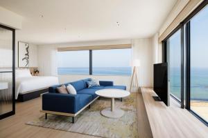 ein Wohnzimmer mit einem blauen Sofa und einem Bett in der Unterkunft Fairfield by Marriott Hyogo Awaji Higashiura in Awaji
