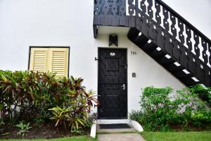 a white house with a black door and stairs at 316 Moonshine in Bridgetown