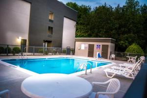 basen ze stołem i krzesłami obok budynku w obiekcie La Quinta Inn & Suites by Wyndham Fayetteville I-95 w mieście Fayetteville