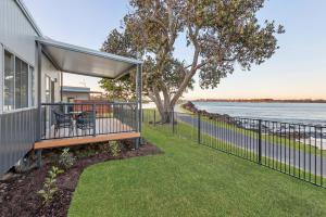 a house with a porch with a bench and a fence at Reflections Shaws Bay - Holiday Park in Ballina