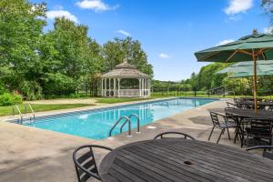 einen Pool mit einem Pavillon, einem Tisch und Stühlen in der Unterkunft Mountaineer Inn in West Dover