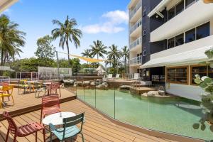 a deck with chairs and tables and a swimming pool at Ocean International Hotel in Mackay