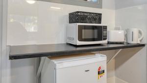 a kitchen with a counter with a microwave and a refrigerator at The Major Mitchell Motel in Bourke