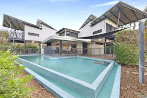 an exterior view of a house with a swimming pool at Reef Villa - A Sprawling Waterfront Oasis in Nightcliff