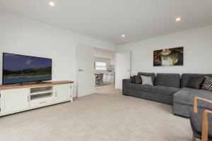 a living room with a couch and a flat screen tv at Coastal Delight - close to the Beach and shops in Papamoa