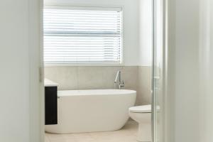 a bathroom with a tub and a toilet and a window at Coastal Delight - close to the Beach and shops in Papamoa