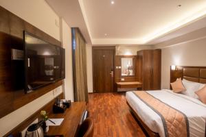 um quarto de hotel com uma cama e uma secretária em Galaxy Golden Fortune Hotel em Bangalore