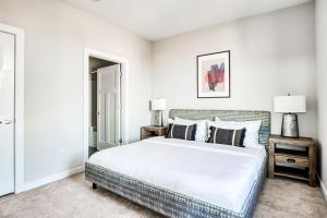 a white bedroom with a large bed and two lamps at CozySuites Music Row Spacious 2BR w free parking01 in Nashville