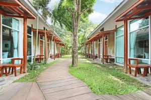 a walkway in front of a building with benches at Nana Resort Kaeng Krachan - SHA Plus Certified in Kaeng Krachan