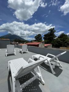 three lounge chairs and a table on a roof at Zoola Suites Antigua in Antigua Guatemala