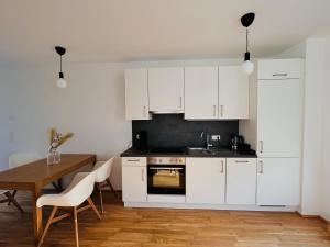 Gemütliche Wohnung mit Flair und Natur pur في فيينا: مطبخ بدولاب بيضاء وطاولة خشبية