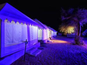 a row of tents are lit up at night at Hindustan Desert Camp in Kūri +8 photos