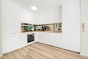 a white kitchen with white cabinets and a wooden floor at Markham Court in Gold Coast