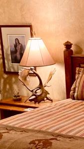 una lámpara sentada en una mesa junto a una cama en Yellowstone Cattle Baron EnSuite, Private Entrance & Parking - Prairie Rose B&B, en Cheyenne