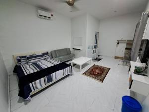 a white bedroom with a bed and a couch at Esah Best INN in Muar