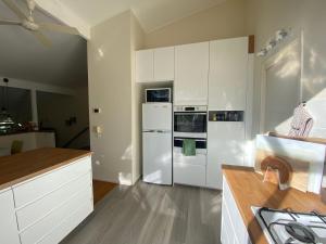 una cocina con armarios blancos y electrodomésticos blancos en Sassafras Treehouse Private home in the Dandenong Ranges, Victoria, en Sassafras