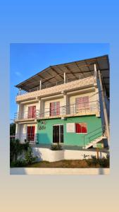 a white and green building with red windows at Casa Guiwa Hostel in Palomino
