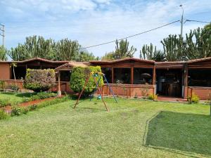 un patio con parque infantil frente a una casa en Bungalows Payancas de Tato, en Barranca