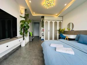 um quarto com uma cama azul e uma televisão de ecrã plano em Khách Sạn Greenhills em Xuan An